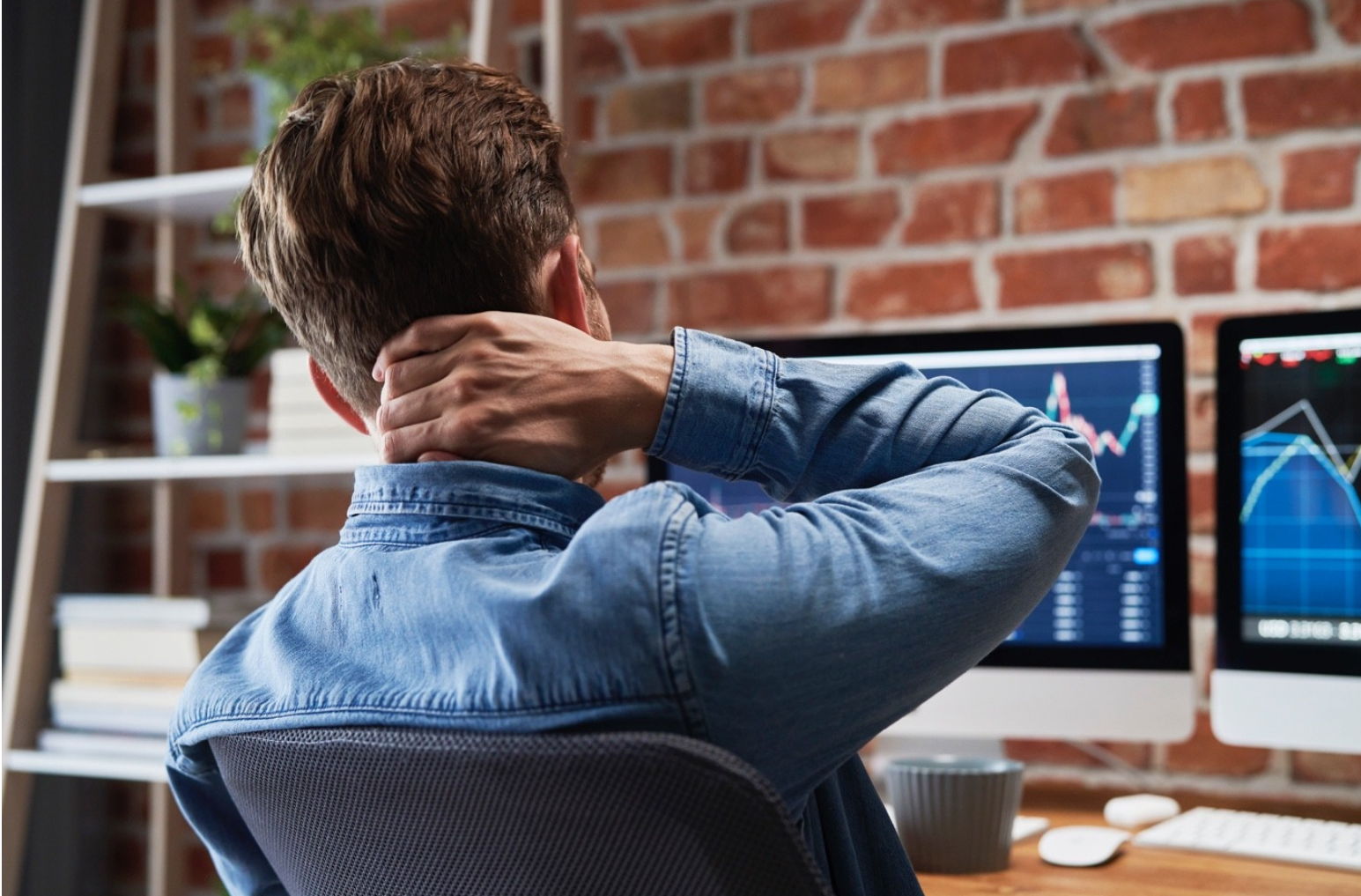 Man sitting at a desk holding his neck, experiencing discomfort from prolonged work, symbolizing the need for relief.