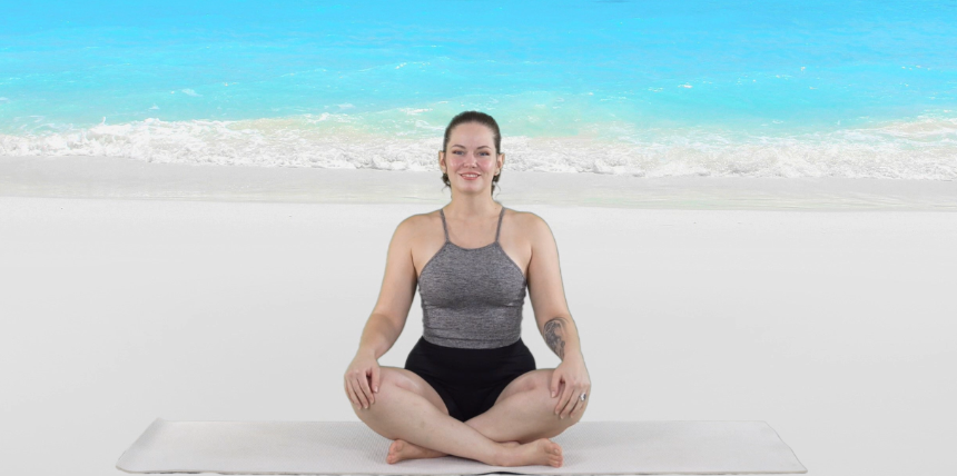 Woman sitting in a yoga pose on a mat by a serene beach, focusing on relaxation and mindfulness.