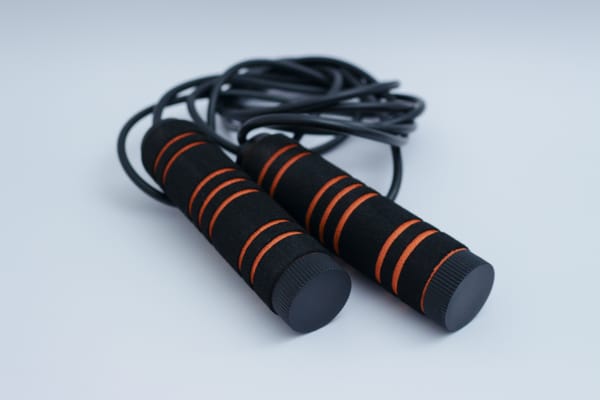 Black and orange jump rope with foam handles, representing equipment for jump rope training