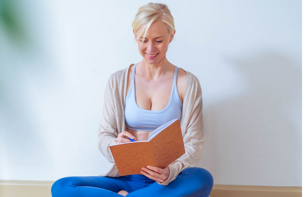 Woman journaling cross-legged, representing a balanced, sustainable approach to health through periodized dieting.