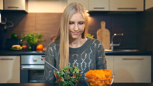 A woman deciding between a bowl of salad and a bowl of chips, representing balance and mindful eating