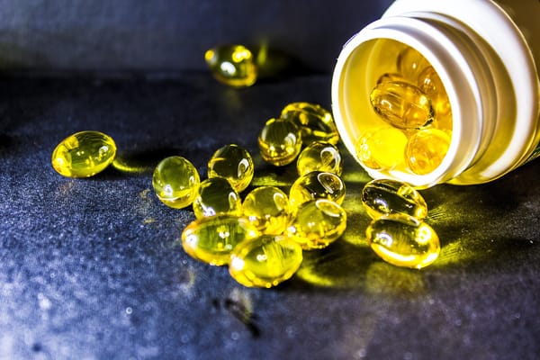 Golden omega-3 capsules spilled from a bottle, representing their role in sports performance, recovery, and brain health.